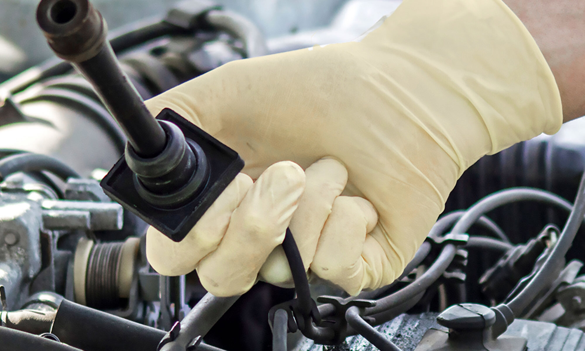 A user works on an engine while wearing Gloveworks heavy-duty latex gloves (ILHD).