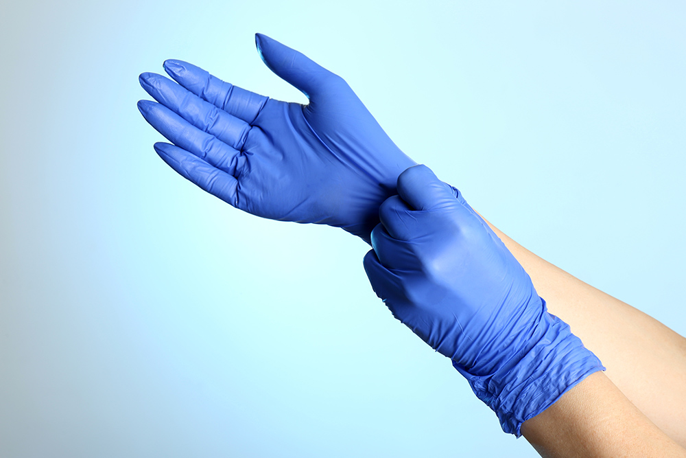 Hands pull on disposable gloves.