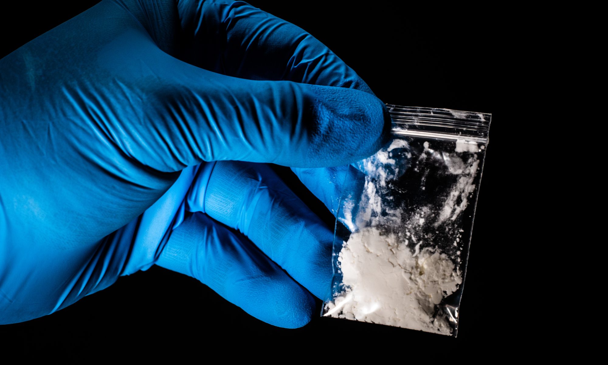 A gloved hands holds a plastic baggie of fentanyl.