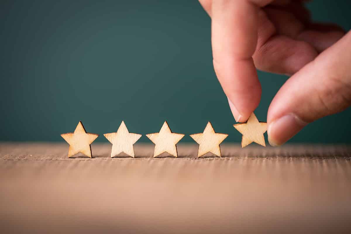 A hand sets up a row of wooden stars to indicate a five-star rating.